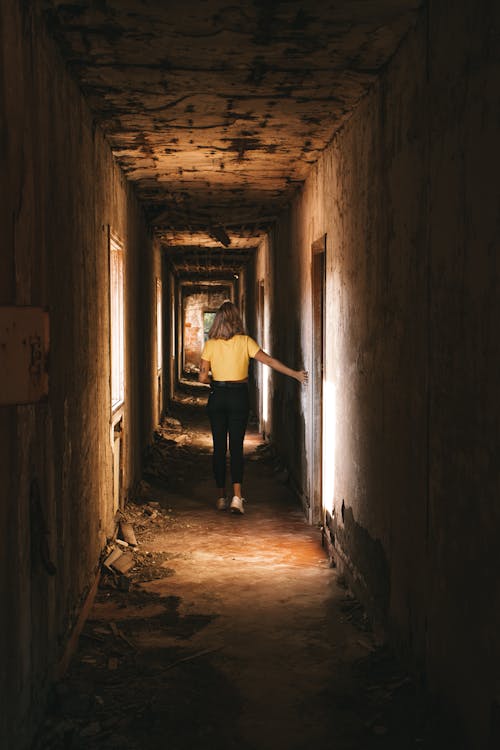 Woman Walking in the Corridor of an Abandoned Building · Free Stock Photo